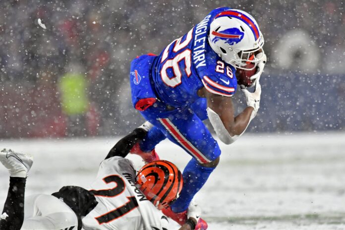Buffalo Bills RB Devin Singletary (26) tries to avoid a tackle against the Bengals in the snow.