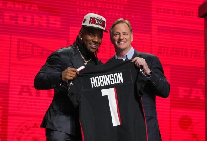 Running back Bijan Robinson and NFL Commissioner Roger Goodell poses with Robinson's jersey after the Atlanta Falcons selected him in the 2023 NFL Draft.