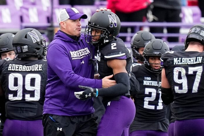 Northwestern Wildcats head coach Pat Fitzgerald hugs defensive back Cameron Mitchell (2).