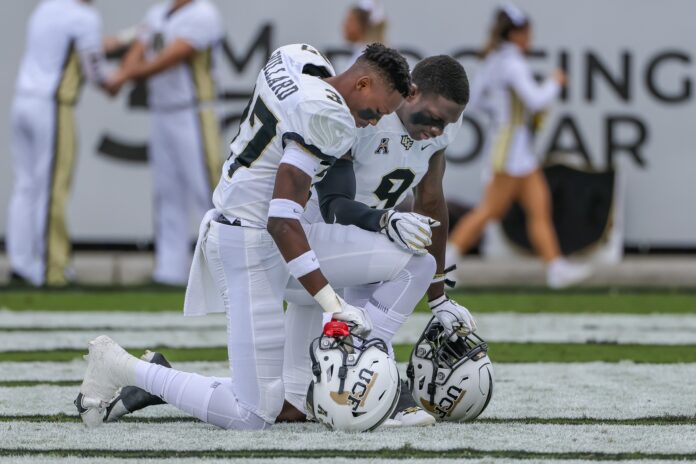 Quadric Bullard and defensive back Divaad Wilson kneel for a moment of silence before the game against the Tulane Green Wave.