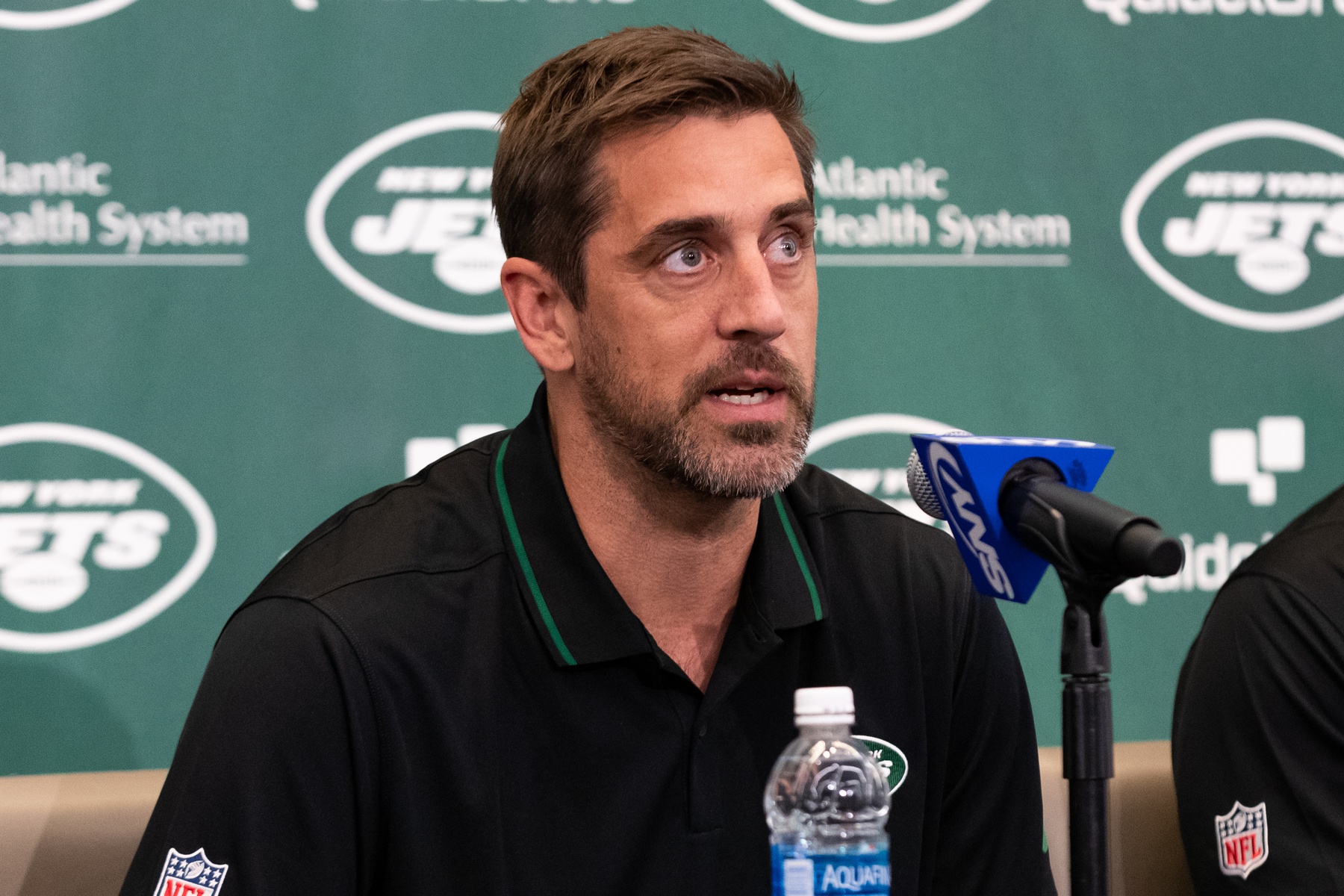 New York Jets QB Aaron Rodgers answering questions from the media at an introductory press conference.