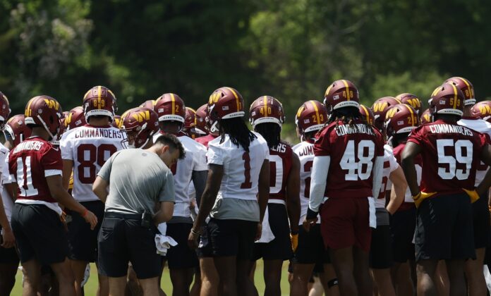 Commanders players huddle during Commanders rookie minicamp at Commanders Park.
