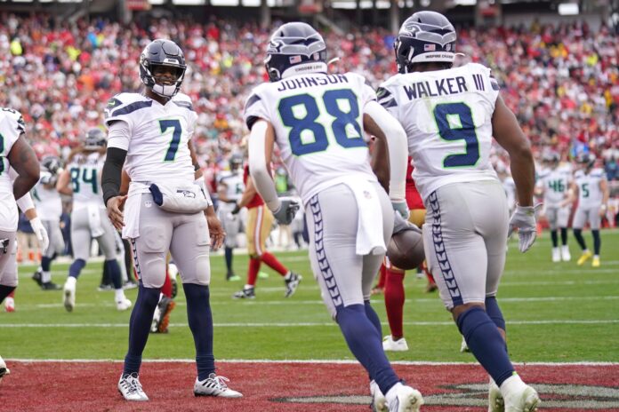 Seattle Seahawks QB Geno Smith (7) celebrates with RB Kenneth Walker III (9) and Cade Johnson (88) after coring a touchdown.
