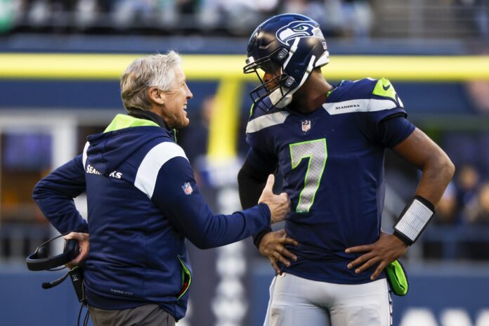 Seattle Seahawks head coach Pete Carroll and QB Geno Smith (7) talk during a timeout.
