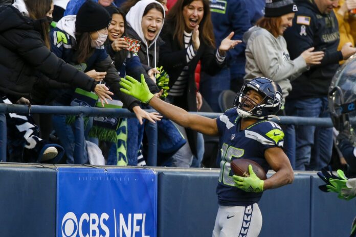 Tyler Lockett (16) celebrates with fans after catching a touchdown pass against the San Francisco 49ers during the third quarter at Lumen Field.