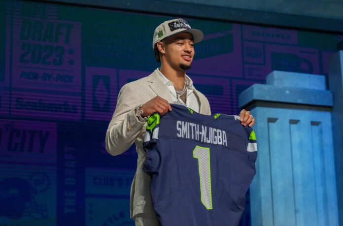 Wide receiver Jaxon Smith-Njigba poses for pictures at the 2023 NFL Draft with his Seahawks jersey after Seattle selected him.