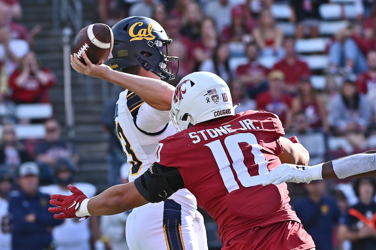 Jack Plummer (13) gets the pass away before getting hit by Washington State Cougars defensive end Ron Stone Jr. (10) in the first half at Gesa Field at Martin Stadium.