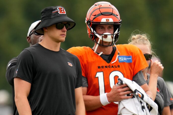 Joe Burrow (9), left, talks with Cincinnati Bengals quarterback Trevor Siemian (19), right, during a joint practice between the Green Bay Packers and the Cincinnati Bengals, Wednesday, Aug. 9, 2023, at the practice fields next to Paycor Stadium in Cincinnati.