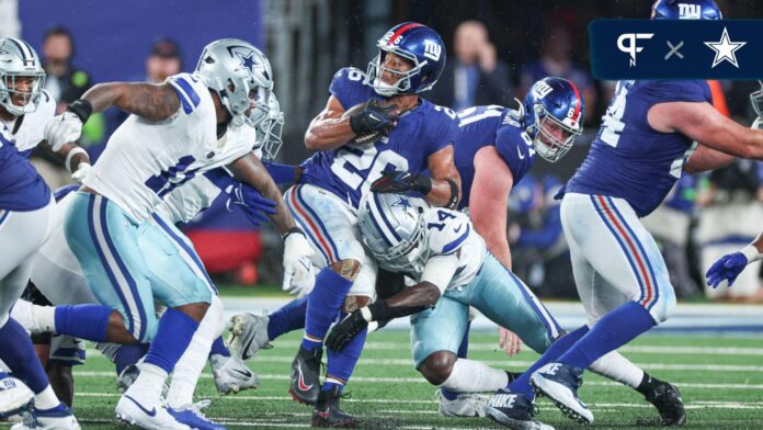 New York Giants running back Saquon Barkley (26) is tackled by Dallas Cowboys safety Markquese Bell (14) during the first half at MetLife Stadium.
