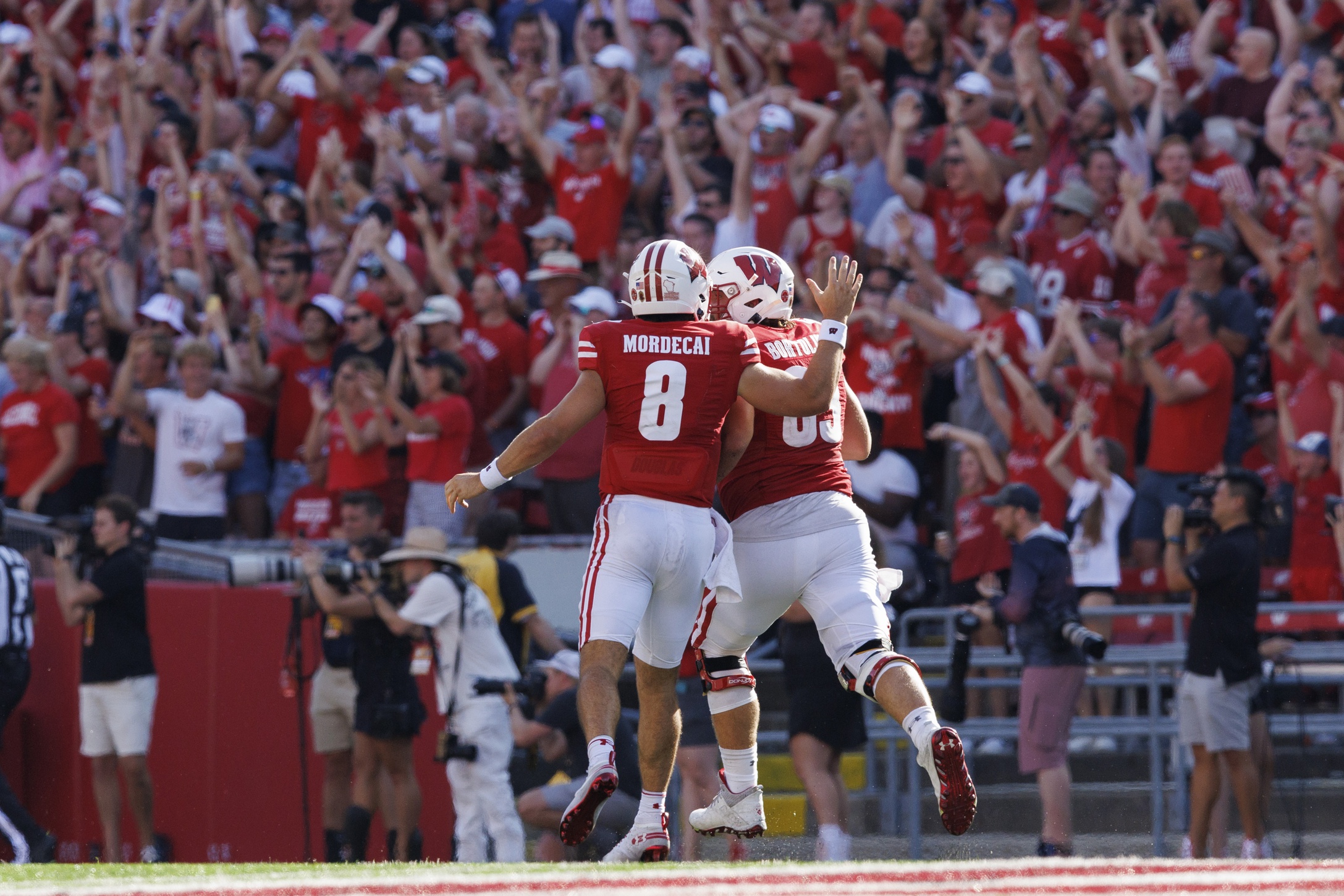 Tanner Mordecai (8) celebrates with offensive linenam Tanor Bortolini (63) following a touchdown during the third quarter against the Buffalo Bulls at Camp Randall Stadium.