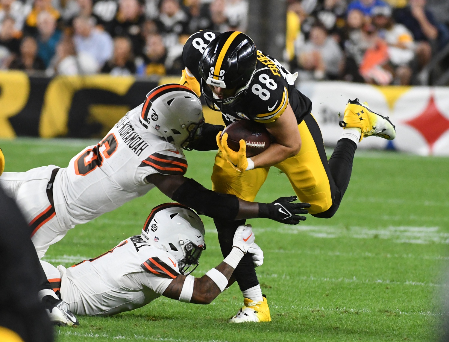 Pat Freiermuth (88) is stopped by Cleveland Browns linebacker Jeremiah Owusu-Koramoah (6) and safety Juan Thornhill (1) during the second quarter at Acrisure Stadium.