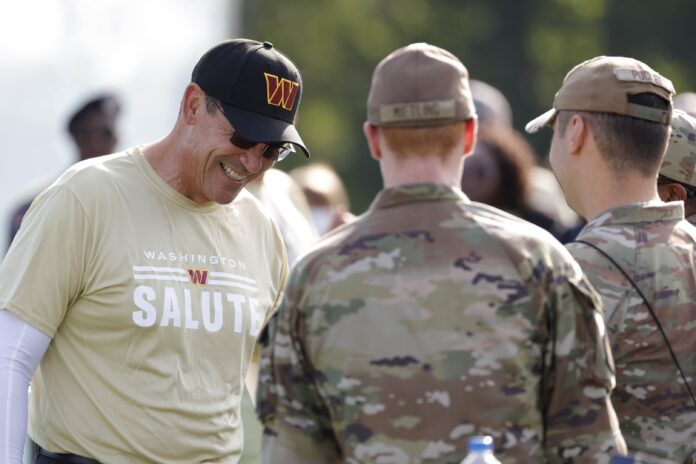 Washington Commanders head coach Ron Rivera (L) speaks with members of the U.S. military during a Salute to Service event prior to day four of Washington Commanders training camp at The Park in Ashburn.
