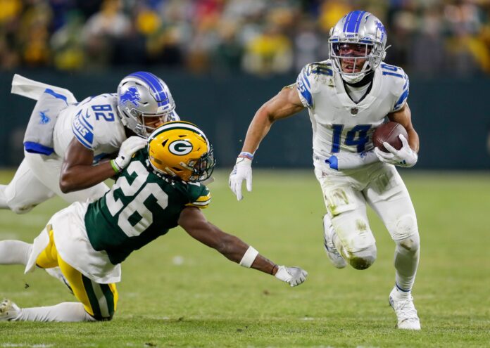 Amon-Ra St. Brown (14) runs the ball after making a reception against the Green Bay Packers.