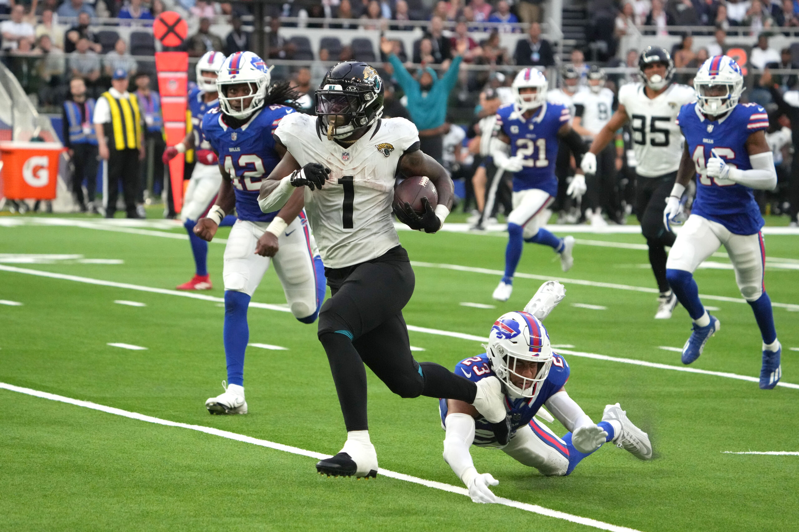 Oct 8, 2023; London United Kingdom; Jacksonville Jaguars running back Travis Etienne Jr. (1) is pursued by Buffalo Bills safety Micah Hyde (23) on a 35-yard touchdown run during the second half of an NFL International Series game at Tottenham Hotspur Stadium. Mandatory Credit: Kirby Lee-USA TODAY Sports