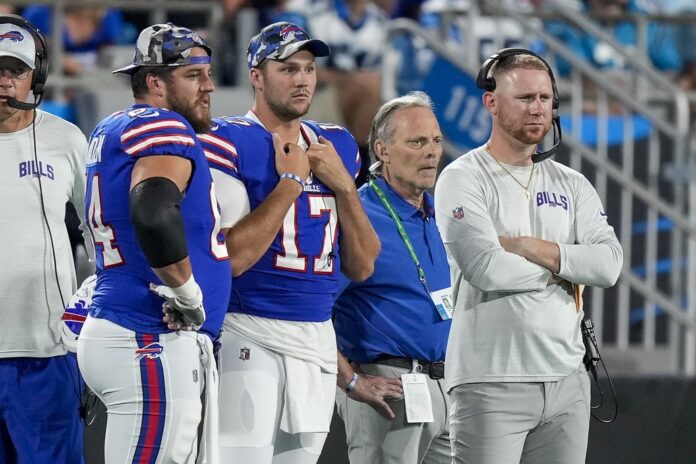 Buffalo Bills guard Greg Van Roten (64), quarterback Josh Allen (17) and offensive coach Joe Brady watch as Carolina Panthers quarterback Sam Darnold (not pictured) is carted off the field.
