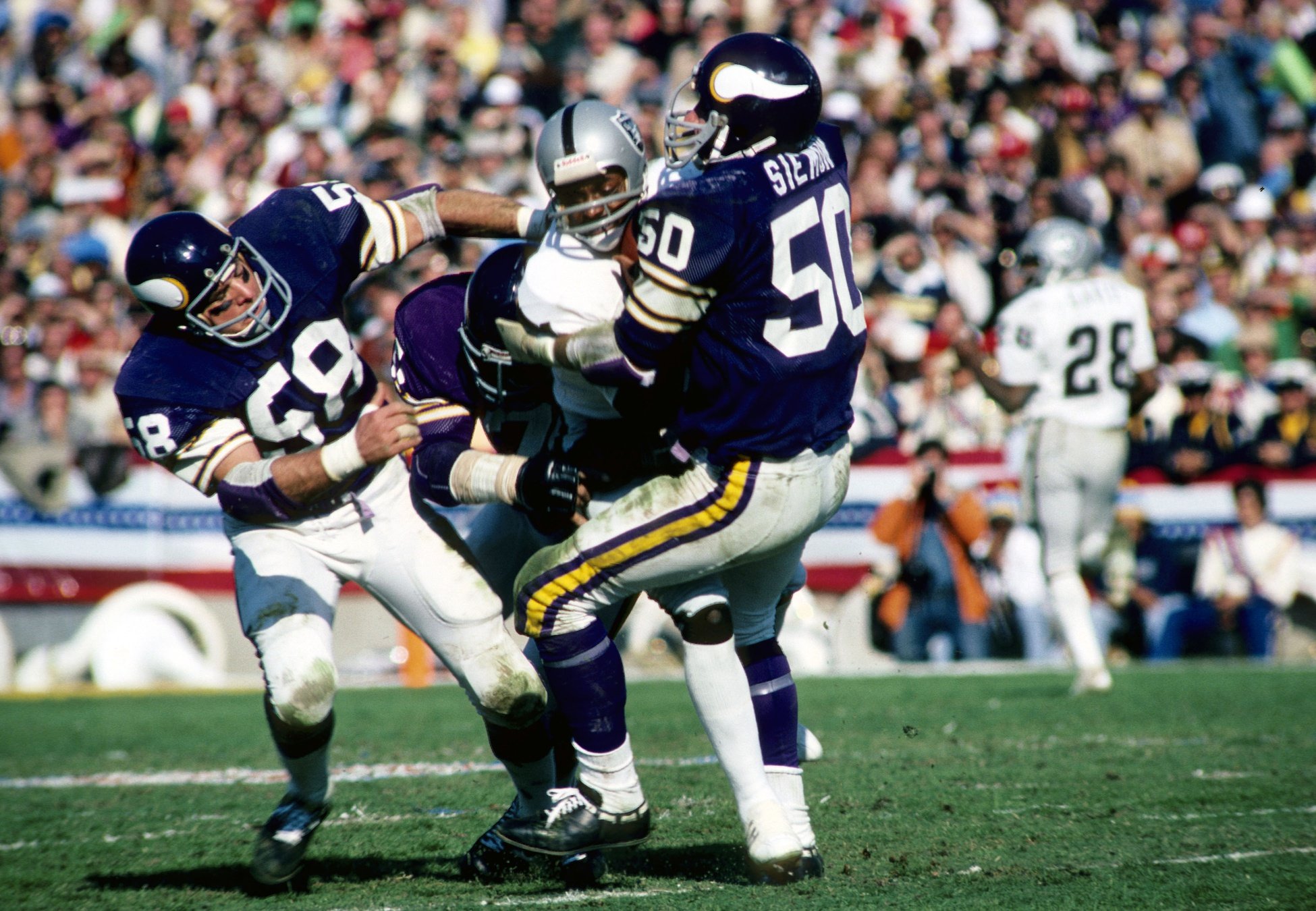 Vikings linebacker (58) Wally Hilgenberg and (50) Jeff Siemon stop Oakland Raiders receiver (21) Cliff Branch in Super Bowl XI at the Rose Bowl.