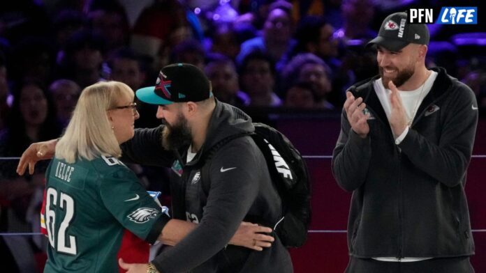 Donna Kelce hugs her son Philadelphia Eagles center Jason Kelce (62) while her other son Kansas City Chiefs tight end Travis Kelce (87) claps at the Footprint Center in downtown Phoenix.