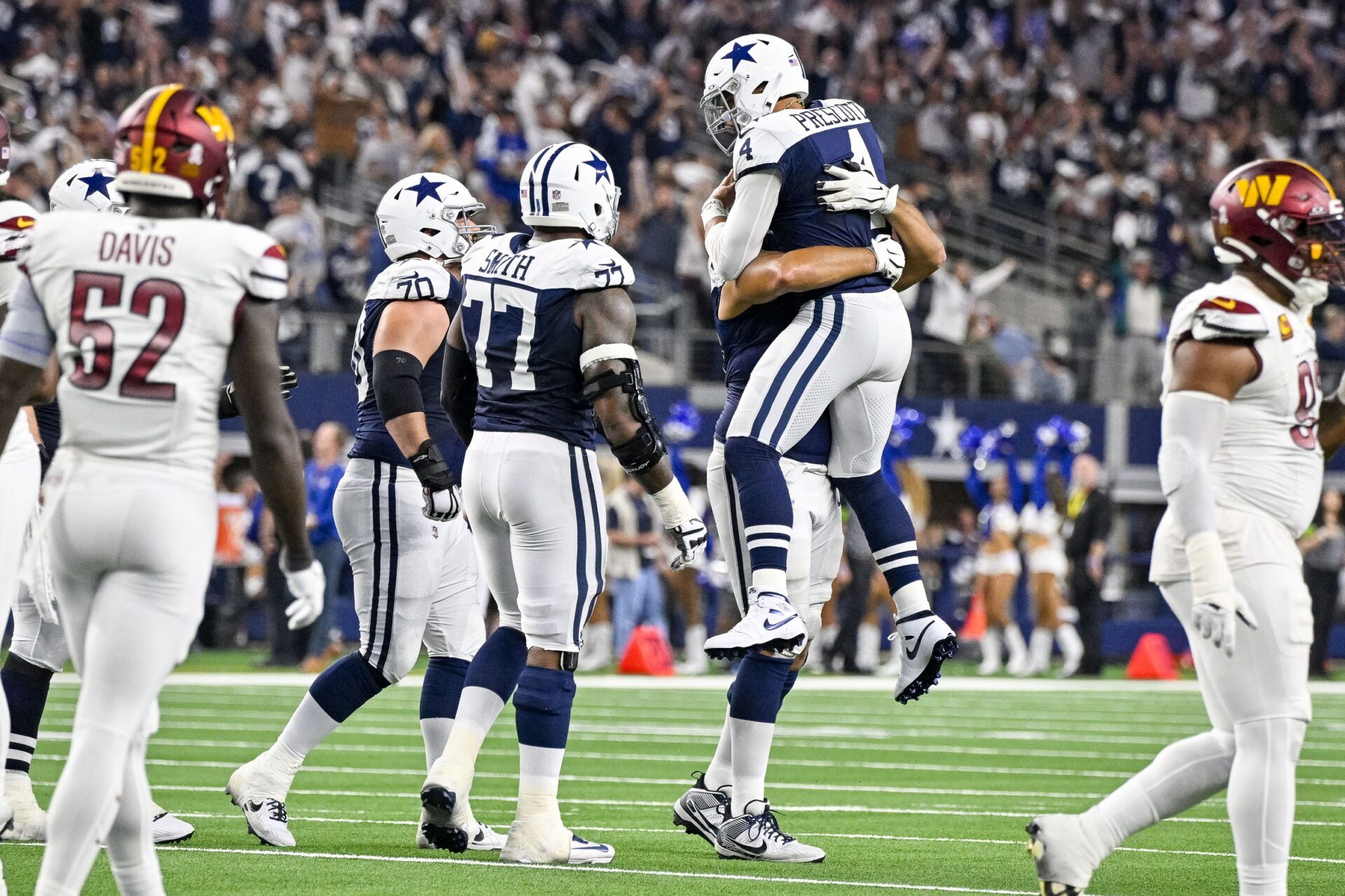 Dallas Cowboys quarterback Dak Prescott (4) celebrates with offensive tackle Tyron Smith (77) and guard Zack Martin (70) after throwing a touchdown pass against the Washington Commanders.