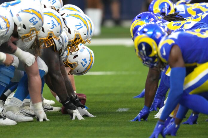 Los Angeles Chargers and Los Angeles Rams helmets at the line of scrimmage as Chargers long snapper Josh Harris (47) snaps the ball at SoFi Stadium.