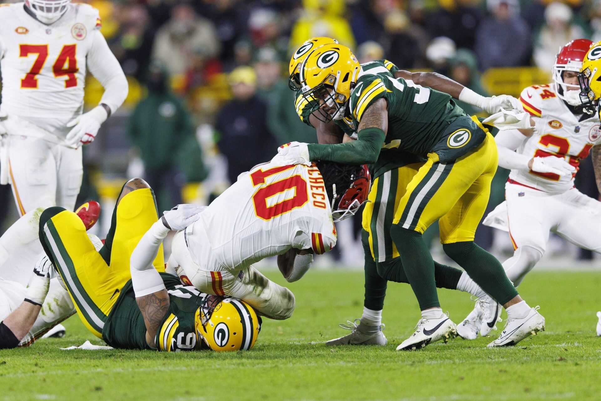 Kansas City Chiefs running back Isiah Pacheco (10) loses his helmet while being tackled by Green Bay Packers linebacker Preston Smith (91) and safety Jonathan Owens (34) during the second quarter at Lambeau Field.