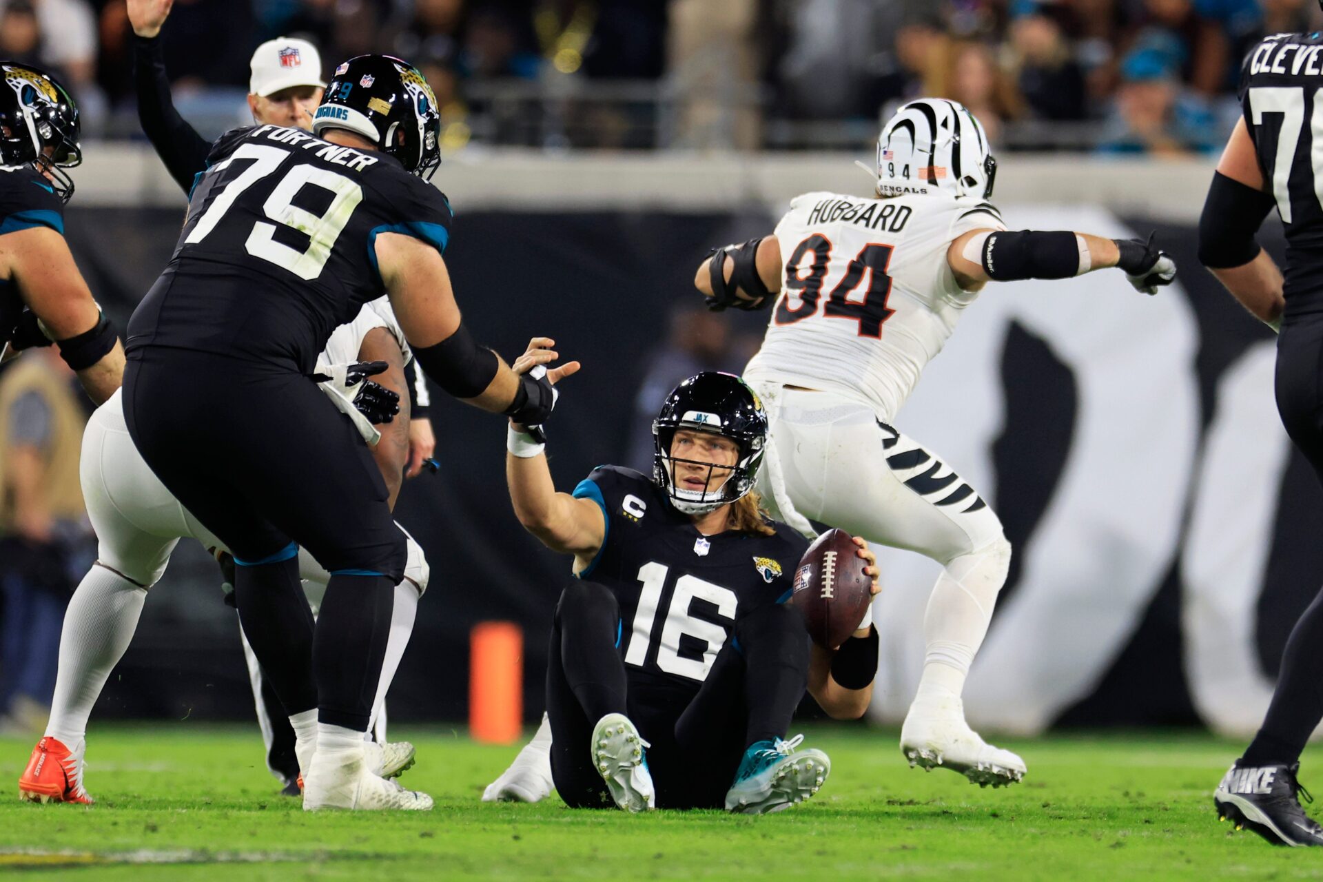 Jacksonville Jaguars QB Trevor Lawrence (16) is helped by an offensive lineman after being sacked.