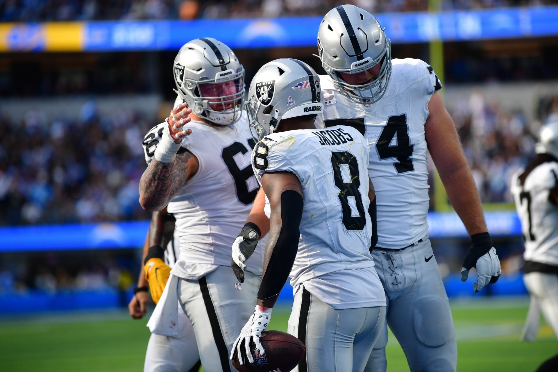 Las Vegas Raiders running back Josh Jacobs (8) celebrates his touchdown scored against the Los Angeles Chargers with guard Dylan Parham (66) and offensive tackle Kolton Miller (74) during the second half at SoFi Stadium.